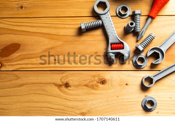 Mechanic tools toy on wood background. Top view.\
Plastic mechanic children Tool toy flat lay background. Space for\
text design.