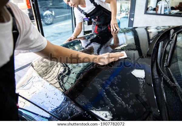 Mechanic with transparent film, car paint\
protection. Mechanic installs car paint protection film. Install\
car paint protection film. Car wrap\
concept.