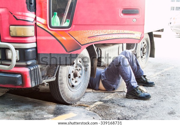 Mechanic under truck repairing dirty greasy oily\
engine with problem.