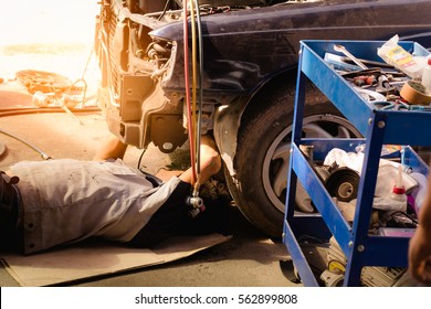 Mechanic in uniform lying down and working under car at auto service garage,selective focus,copy space. - Powered by Shutterstock