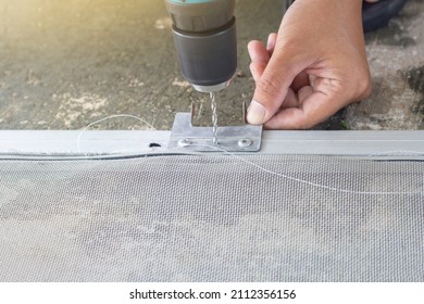 Mechanic Uses Automatic Screwdriver To Drill Aluminum Sheet To Fix The Mosquito Net Wire Mesh Screen.