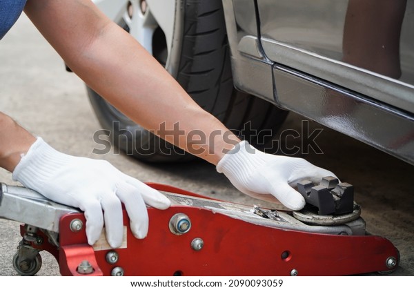 mechanic uses\
the jack to lift the car to fix the car\'s suspension.Seasonal tyre\
change or service abstract\
concept.