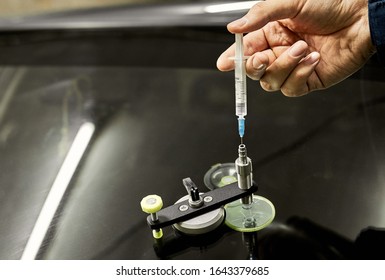 A Mechanic Uses Repair Equipment To Repair A Damaged Windshield. It Repairs Glass Chips With An Injector Under Pressure And Uses A Special Polymer.