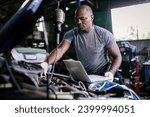 Mechanic using compute for Diagnostic  machine tools ready to be used with car. Car mechanic using a computer laptop to diagnosing and check up on car engines parts for fixing and repair