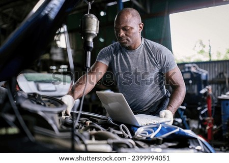Mechanic using compute for Diagnostic  machine tools ready to be used with car. Car mechanic using a computer laptop to diagnosing and check up on car engines parts for fixing and repair