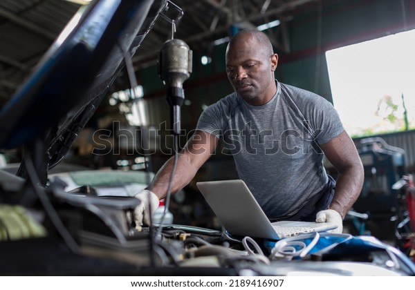 Mechanic\
using compute for Diagnostic  machine tools ready to be used with\
car. Car mechanic using a computer laptop to diagnosing and check\
up on car engines parts for fixing and\
repair