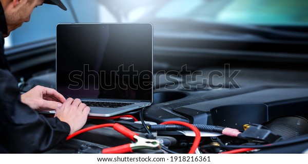 Mechanic using\
computer for diagnostics engine. Repairing car. Blur garage auto\
repair service in\
background.