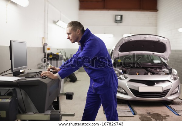Mechanic using a computer in\
a garage
