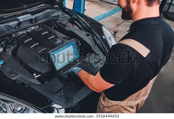 Mechanic using Diagnostic\
machine tools ready to be used with car. High angle view. Selective\
focus.