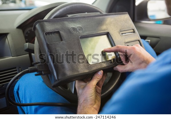 Mechanic using diagnostic tool in the car at the\
repair garage