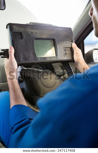Mechanic using diagnostic tool in the car at the\
repair garage