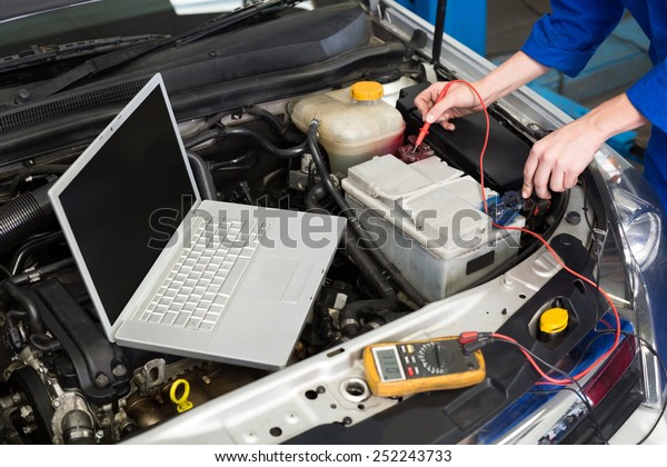 Mechanic using diagnostic tool on engine at the\
repair garage