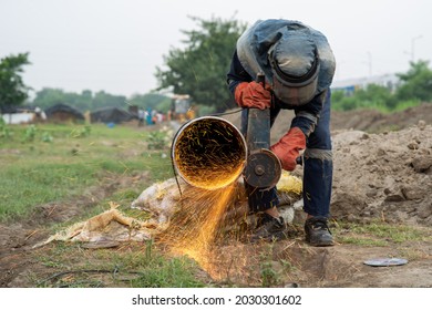 Mechanic Using Electric Grinder Tool With Protective Work Wear During Installation Of Natural Gas Pipeline In India, 