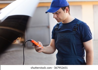 Mechanic Using An Electronic Tester On A Car Engine