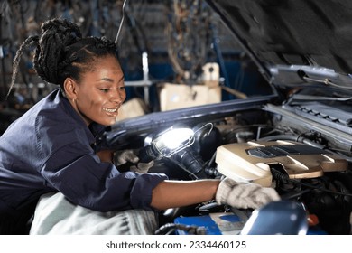 mechanic using flashlight for checking and fixing a car in automobile repair shop