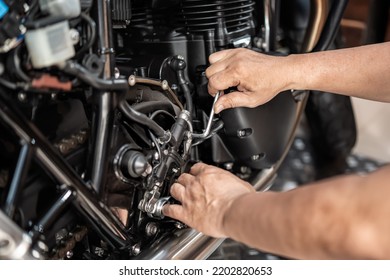 Mechanic using a Hex key or Allen wrench to remove Motorcycle rear Hydraulic brake pump, working in garage .maintenance and repair motorcycle concept .selective focus