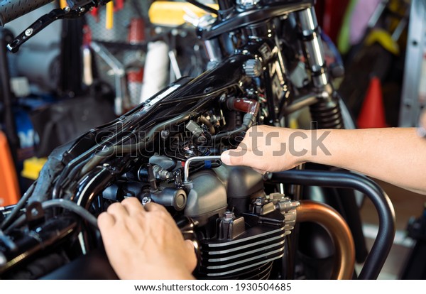 mechanic using Hex Key Wrench working on motorcycle\
at motorbike garage , concept of motorcycle maintenance and repair\
. selective focus