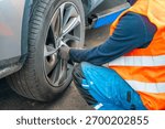 Mechanic using an impact wrench to remove lug nuts from a car wheel. Seasonal tire change and professional car service in preparation for winter. High quality photo
