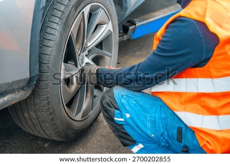 Mechanic using an impact wrench to remove lug nuts from a car wheel. Seasonal tire change and professional car service in preparation for winter. High quality photo