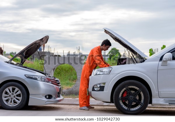 Mechanic\
using a laptop computer to check a car engine\
.