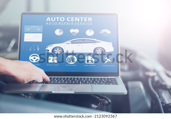 Mechanic using a laptop computer to check\
collect information during work a car engine, technology for\
vehicle maintenance\
concept.