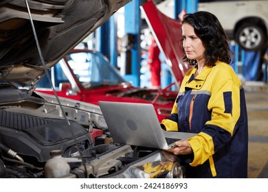 mechanic using laptop computer for checking and fixing a car in automobile repair shop