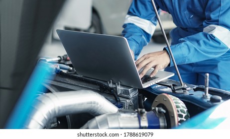 Mechanic using laptop computer working tuning on car for the efficiency of the race car in garage.maintenance concept
