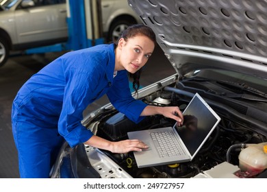 Mechanic using laptop on car at the repair garage - Powered by Shutterstock