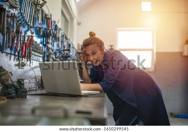  Mechanic using laptop at the\
repair garage. Young female mechanic with laptop. Business woman at\
a factory. Mechanic typing on a laptop at the repair\
garage