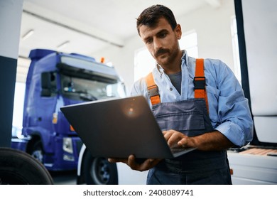 Mechanic using laptop while working at truck repair workshop. - Powered by Shutterstock