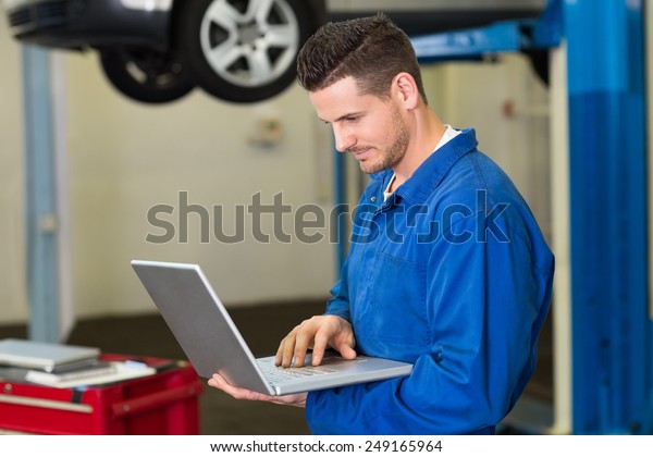 Mechanic\
using a laptop to work at the repair\
garage