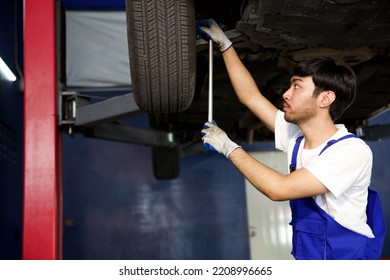 Mechanic Using Ratchet Wrench And Fixing Underneath The Car