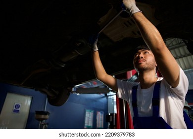 Mechanic Using Ratchet Wrench And Fixing Underneath The Car