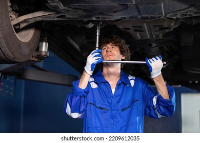 Mechanic Using Ratchet Wrench And Fixing Underneath The Car