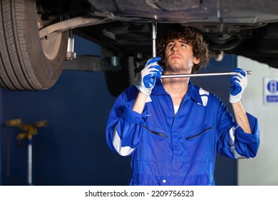 Mechanic Using Ratchet Wrench And Fixing Underneath The Car