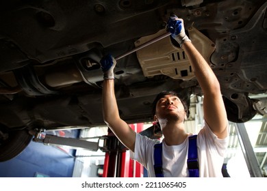 Mechanic Using Ratchet Wrench And Fixing Underneath The Car