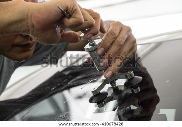 Mechanic using repairing equipment to fix\
damaged windshield, windshield\
repairing,