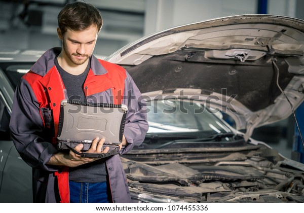 mechanic using special laptop computer to check\
car engine