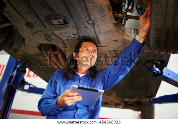 Mechanic using\
tablet computer when checking\
car
