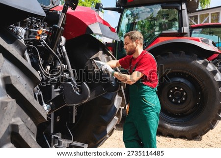 Mechanic using tablet to inspect tractor outdoors