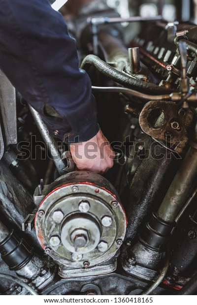 Mechanic using a wrench on the engine of a big\
motor during a service or repair in an automotive workshop, close\
up of his hands -\
Image