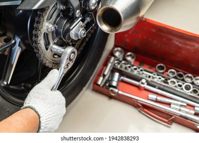 Mechanic using a wrench and socket on motorcycle sprocket   .maintenance and repair concept in motorcycle garage .selective focus 