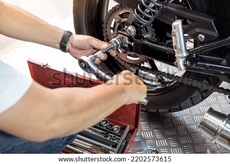 Mechanic using a wrench and socket to Remove and Replace Rear Motorcycle Wheel, working in garage maintenance, repair motorcycle concept  .selective focus