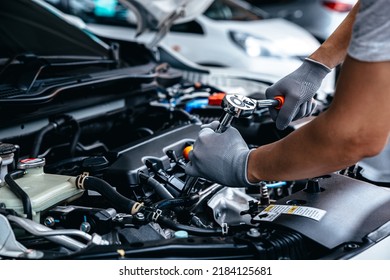 Mecánica con llave mientras trabaja en el motor de coches en taller de taller de garaje, autoservicio de coches y concepto de comprobación de mantenimiento.