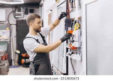 Mechanic wearing gloves organizing tools on a wall rack in a garage workshop. Focused on efficiency in a professional automotive repair setting. - Powered by Shutterstock