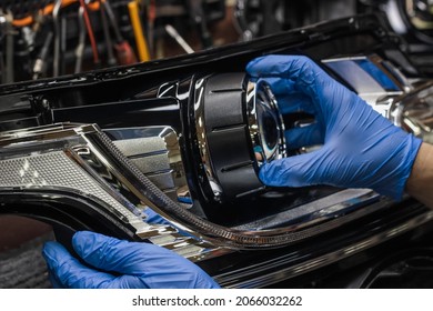 A mechanic wearing rubber gloves installs an LED lens into the headlight housing.Car headlight during repair and cleaning.The mechanic restores the headlight of the car.Restoration of automotive optic