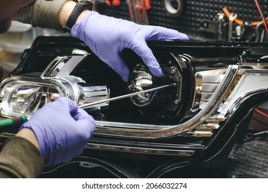 A Mechanic Wearing Rubber Gloves Installs An LED Lens Into The Headlight Housing.Car Headlight During Repair And Cleaning.The Mechanic Restores The Headlight Of The Car.Restoration Of Automotive Optic