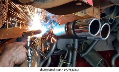 Mechanic or welder is fixing a car exhaust system by welding the exhaust pipe