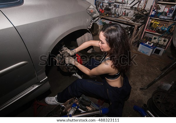 A\
mechanic women repairing an engine of an old\
car.
