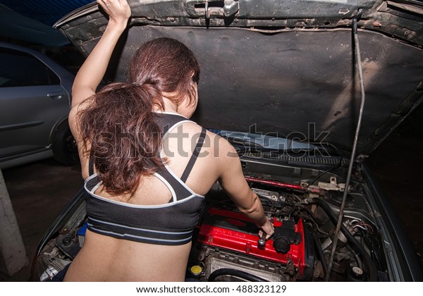 A
mechanic women repairing an engine of an old
car.